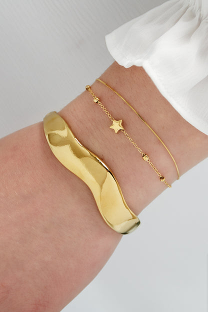 Gouden wave bangle armband van roestvrij staal gedragen om de pols